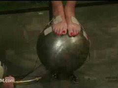 a pain slut is balancing on an overheated steel ball