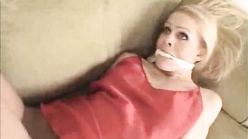 Blonde cutie Ashley Roberts struggles against her bondage on the sofa